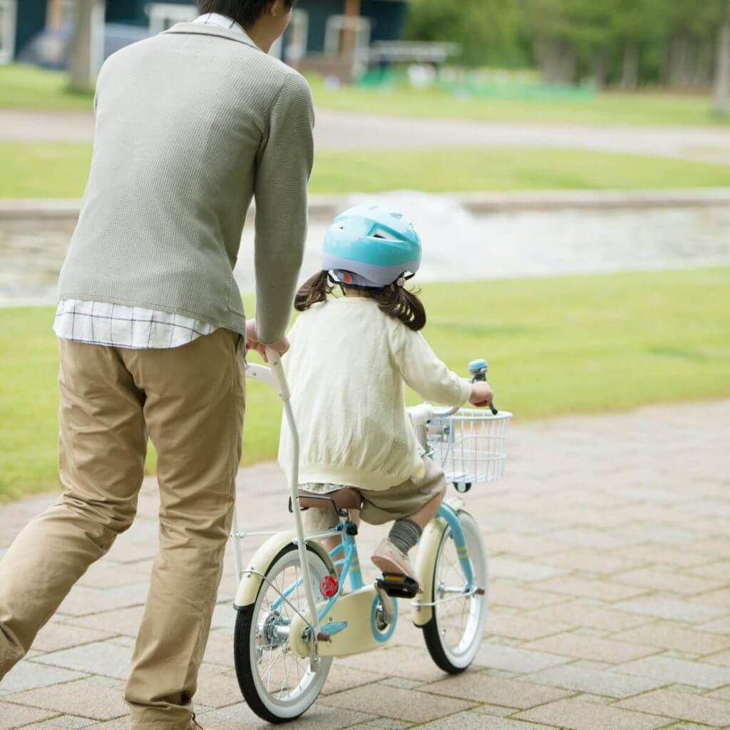 自転車に乗る女の子とサポートするパパ