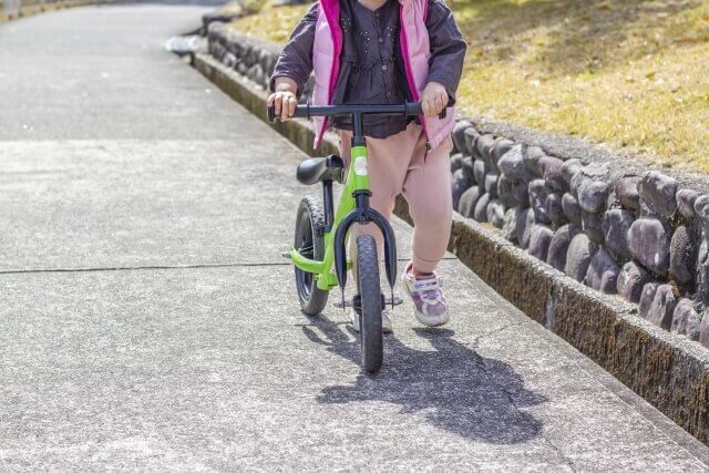 女の子がキックバイクを押している様子