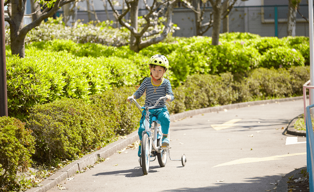 補助輪付き自転車に乗る子ども