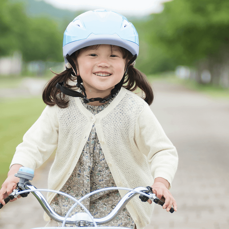 ヘルメットをかぶり笑顔で自転車にのる女の子